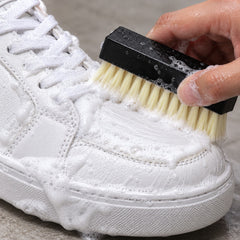 Cleaning a white sneaker with the kit brush